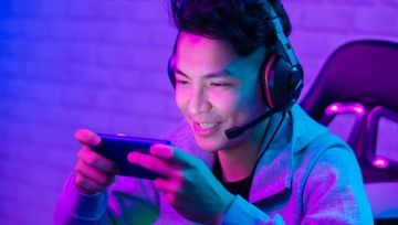 young man with headphones watching a streamer on his phone