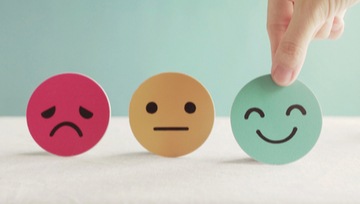 3 smiley faces - one frowning, one neutral, one smiling - with a hand choosing the smiling face