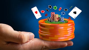 a hand holding a stack of casino chips with cards flying around