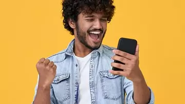 man looking at his phone and celebrating 