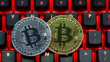 two bitcoins sitting on a black and red computer keyboard