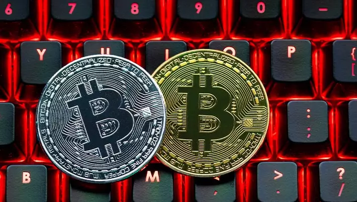 two bitcoins sitting on a black and red computer keyboard