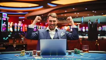 man celebrating with a laptop and a casino background