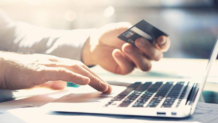 man holding a credit card while typing on a computer