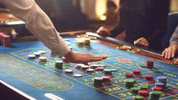casino gaming table with dealer and people sitting around    