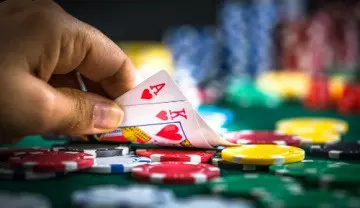 A hand showing the A and K of hearts on a poker table full of chips