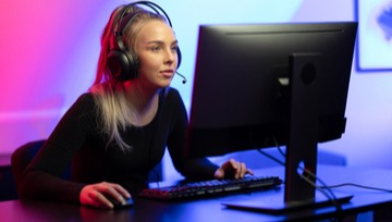 woman gamer wearing her headset playing on her computer